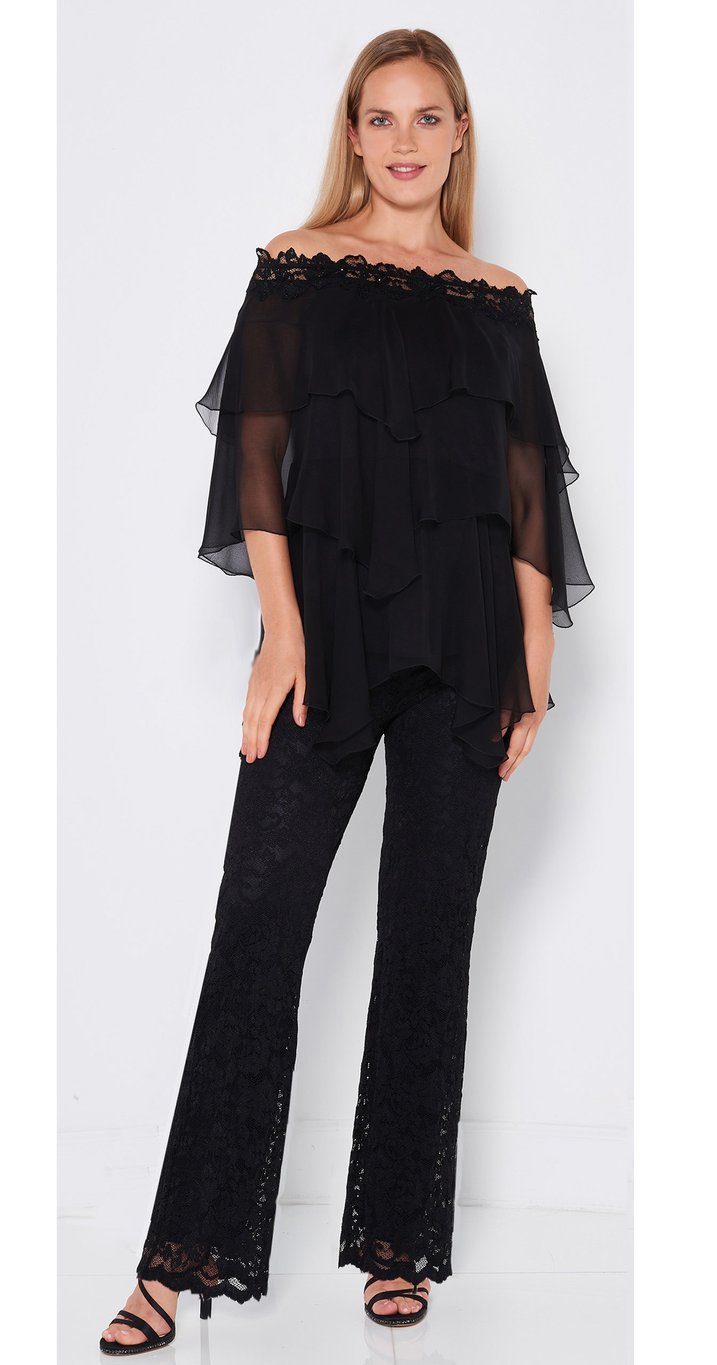 Woman wearing a black off-shoulder top and black lace pants on a white background