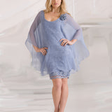 Woman wearing a light blue silver lace dress with chiffon overlay on a white background