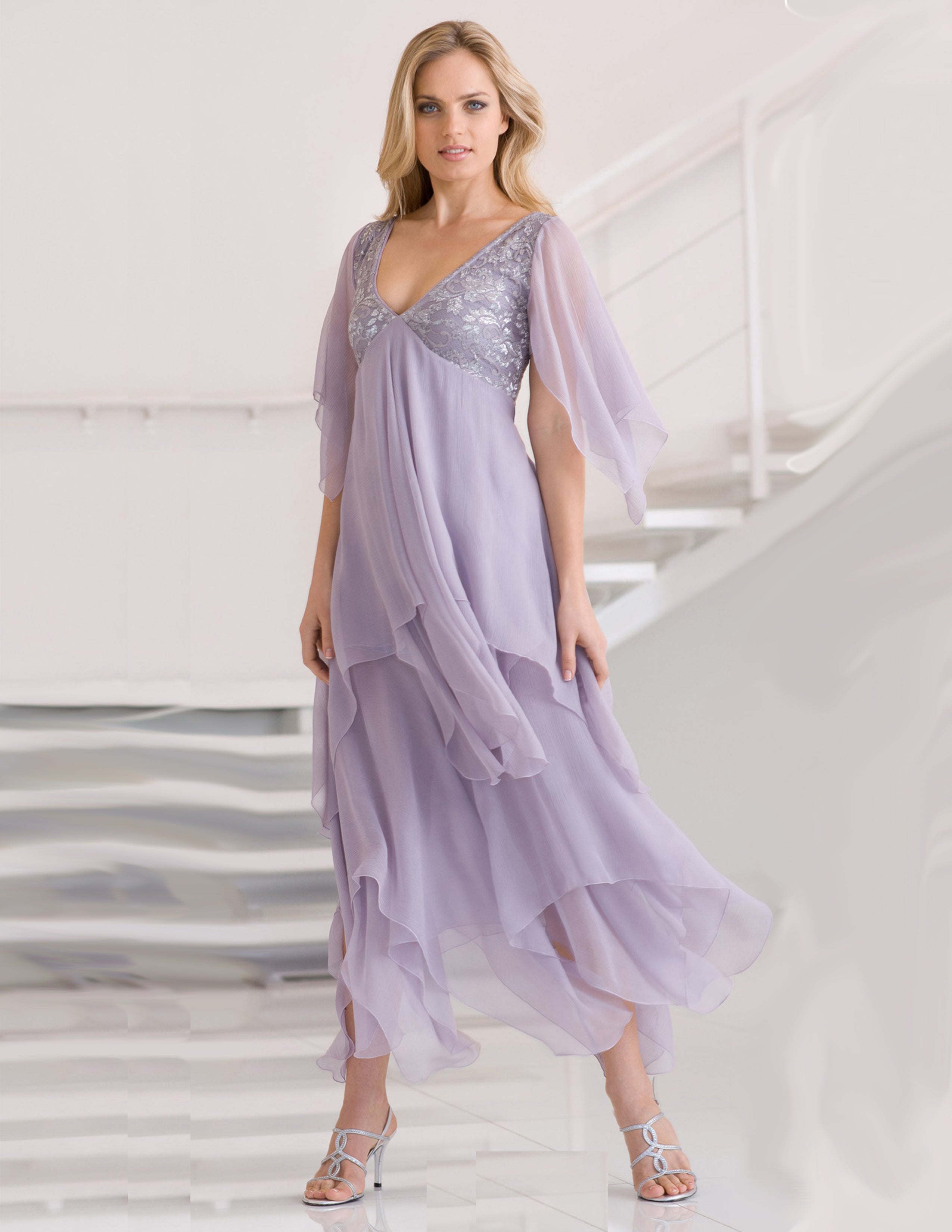 Woman wearing a lavender evening gown with a silver lace bodice on a white background