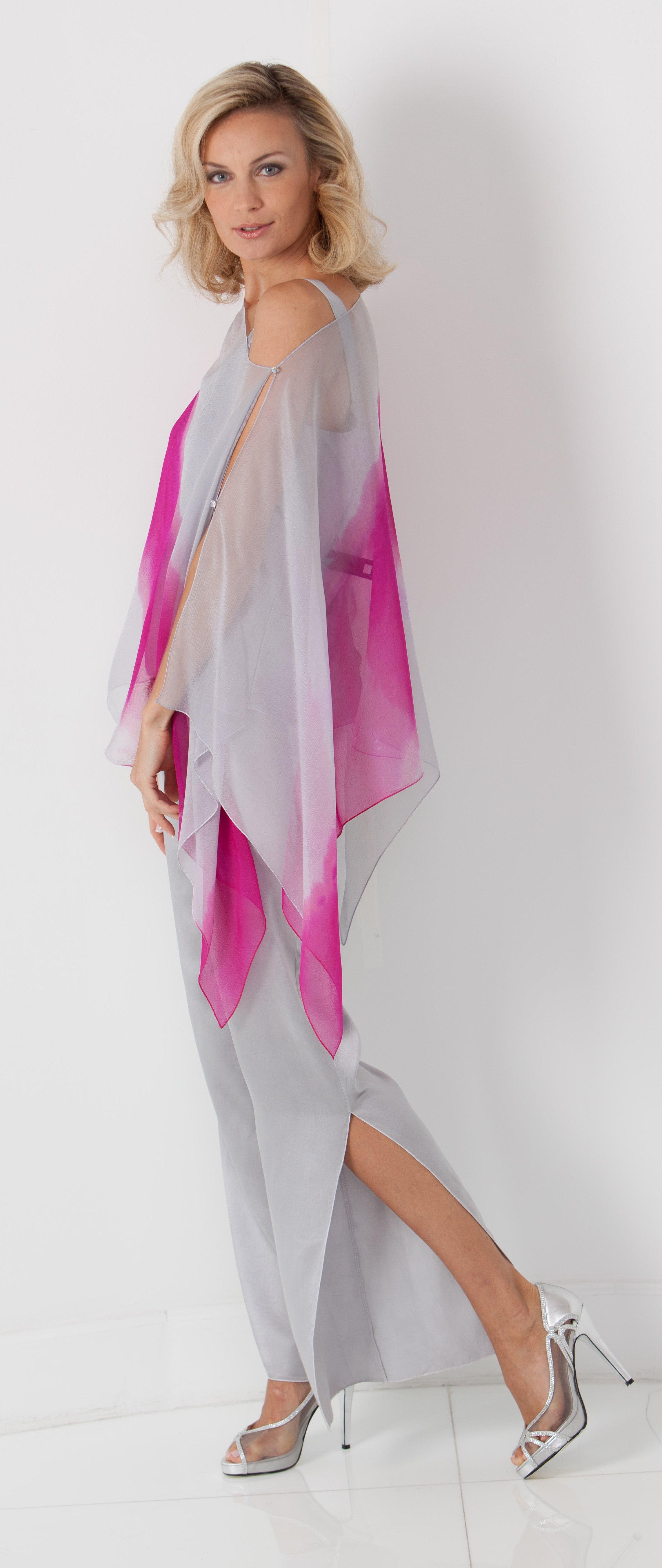 Woman wearing gray pants with a pink and gray poncho on a white background