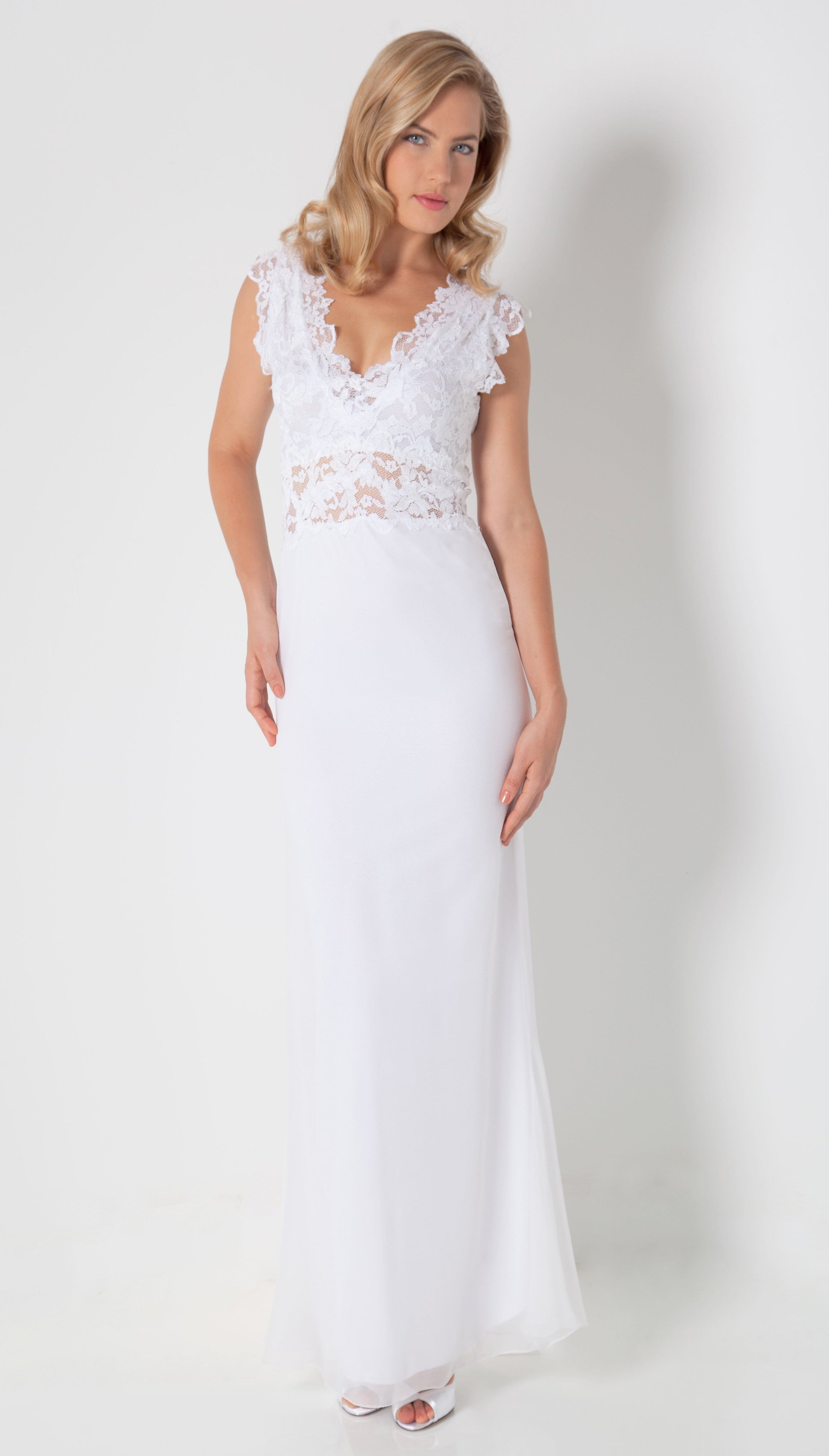 Woman in Full Length French Lace and Silk Plisse' white dress standing against a white wall