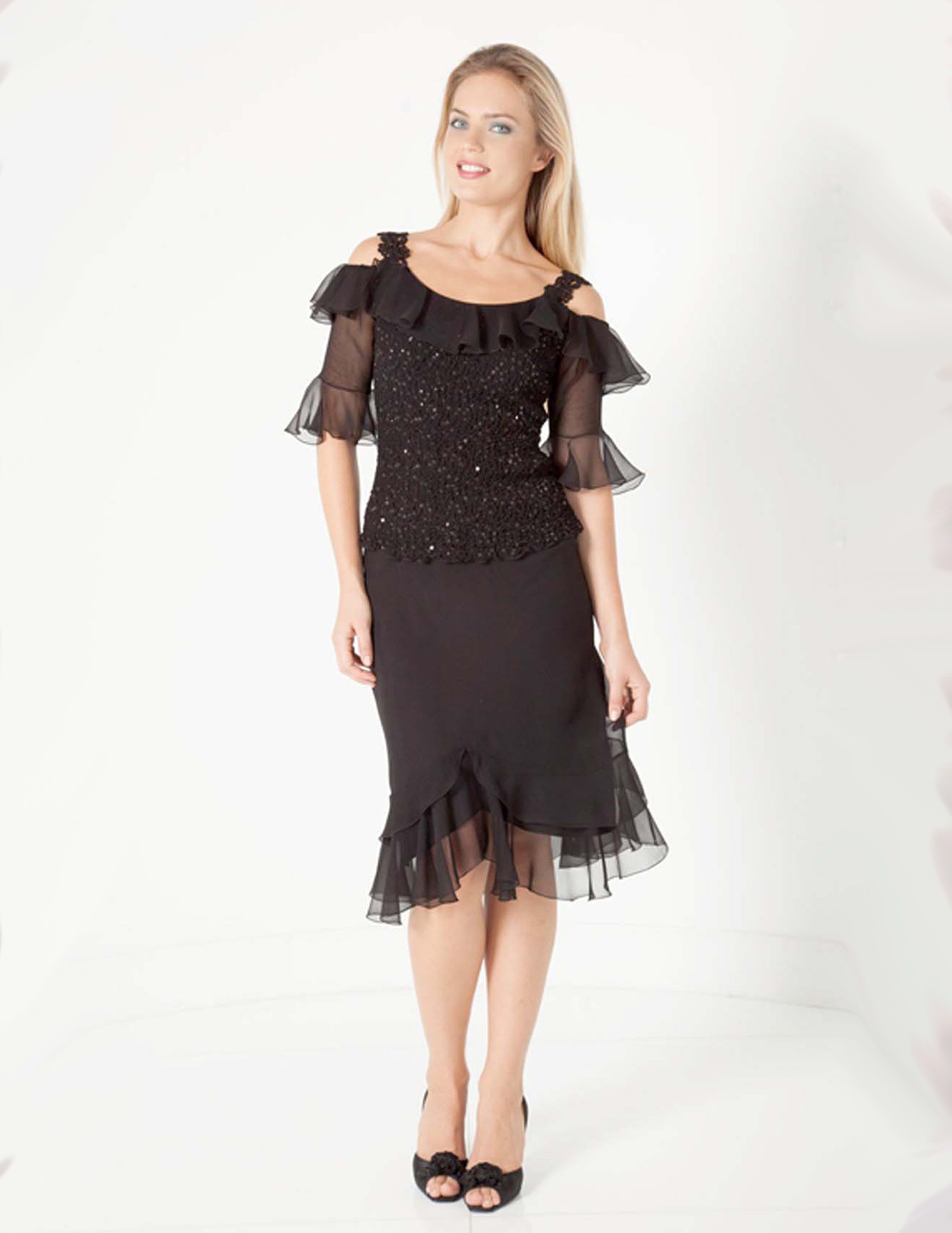 Woman wearing a black silk with sheer sleeves with a skirt on a white background