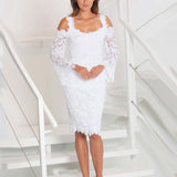 Woman wearing a white lace dress standing on a staircase.