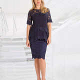 Woman wearing a navy plisse and lace blouse and skirt against a white background