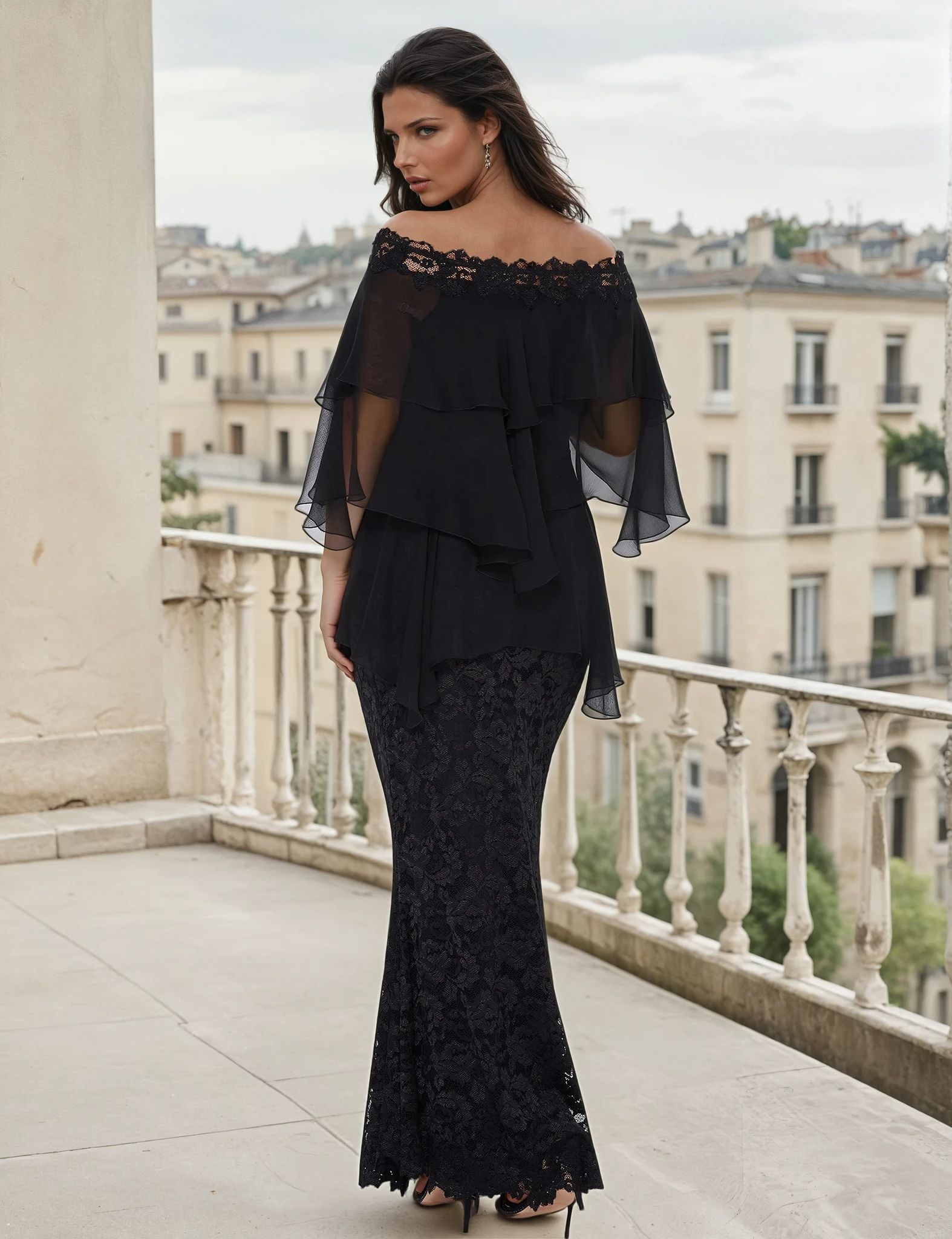 Woman wearing a black layered off the shoulder blouse with a long lace mermaid skirt on a balcony