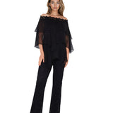 Woman wearing a black off-shoulder top and black lace pants on a white background