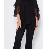 Woman wearing a black off-shoulder top and black lace pants on a white background