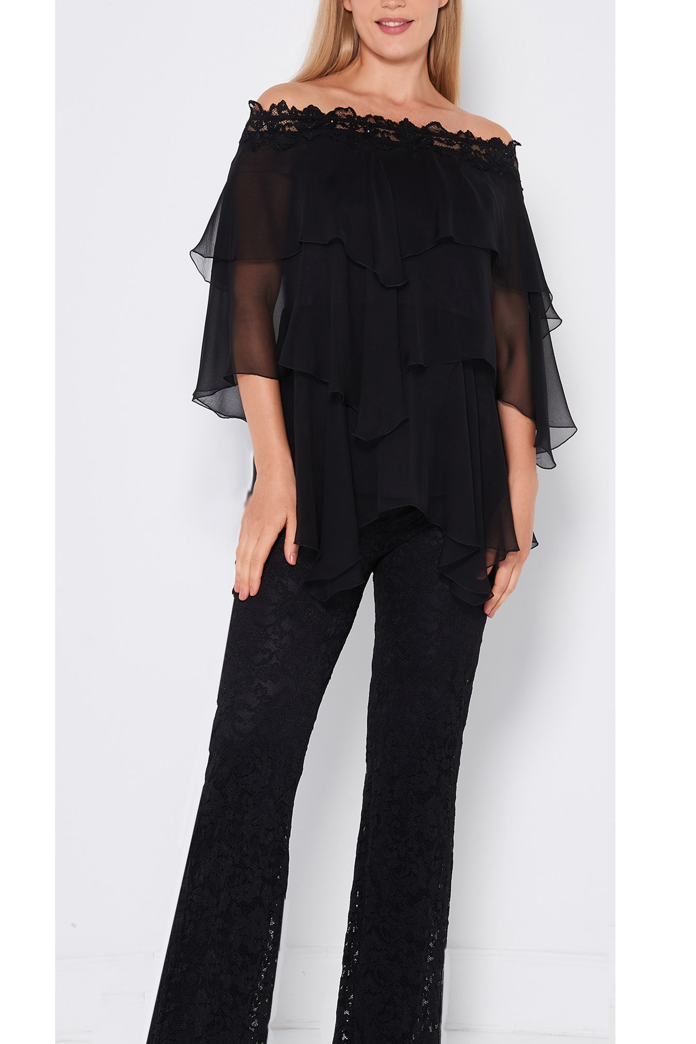 Woman wearing a black off-shoulder top and black lace pants on a white background
