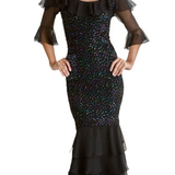 Woman models D1560SC by Sara Mique Evening Wear—a fitted black cold-shoulder dress with ruffled sheer sleeves, a layered skirt, and iridescent sequin pucker embellishments. She pairs it with black open-toe heels.