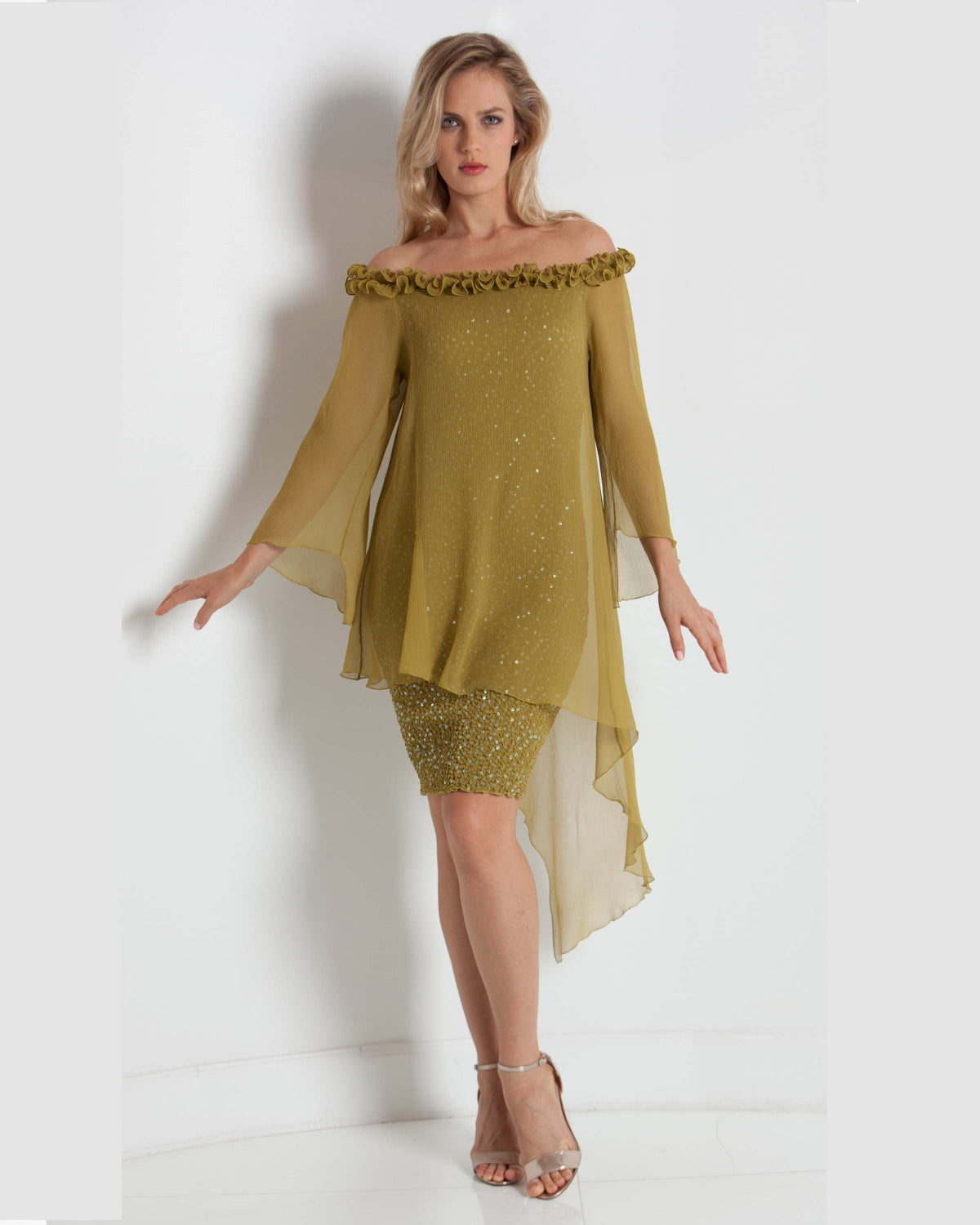 Woman wearing a green off-shoulder dress with sheer sleeves on a white background