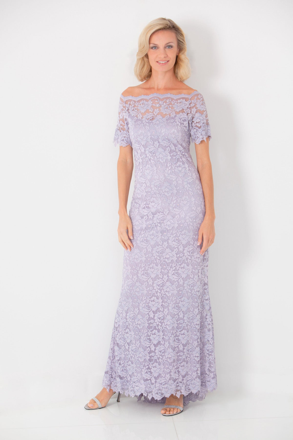 Woman wearing a long, light cassis lace dress against a white background