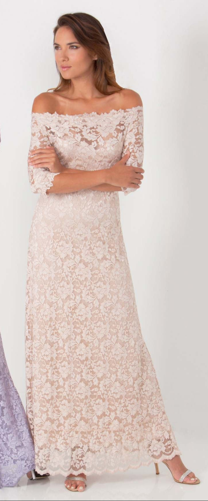 Woman wearing a long, off-shoulder lace dress on a white background
