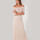 Woman wearing a white lace off-shoulder dress on a plain background