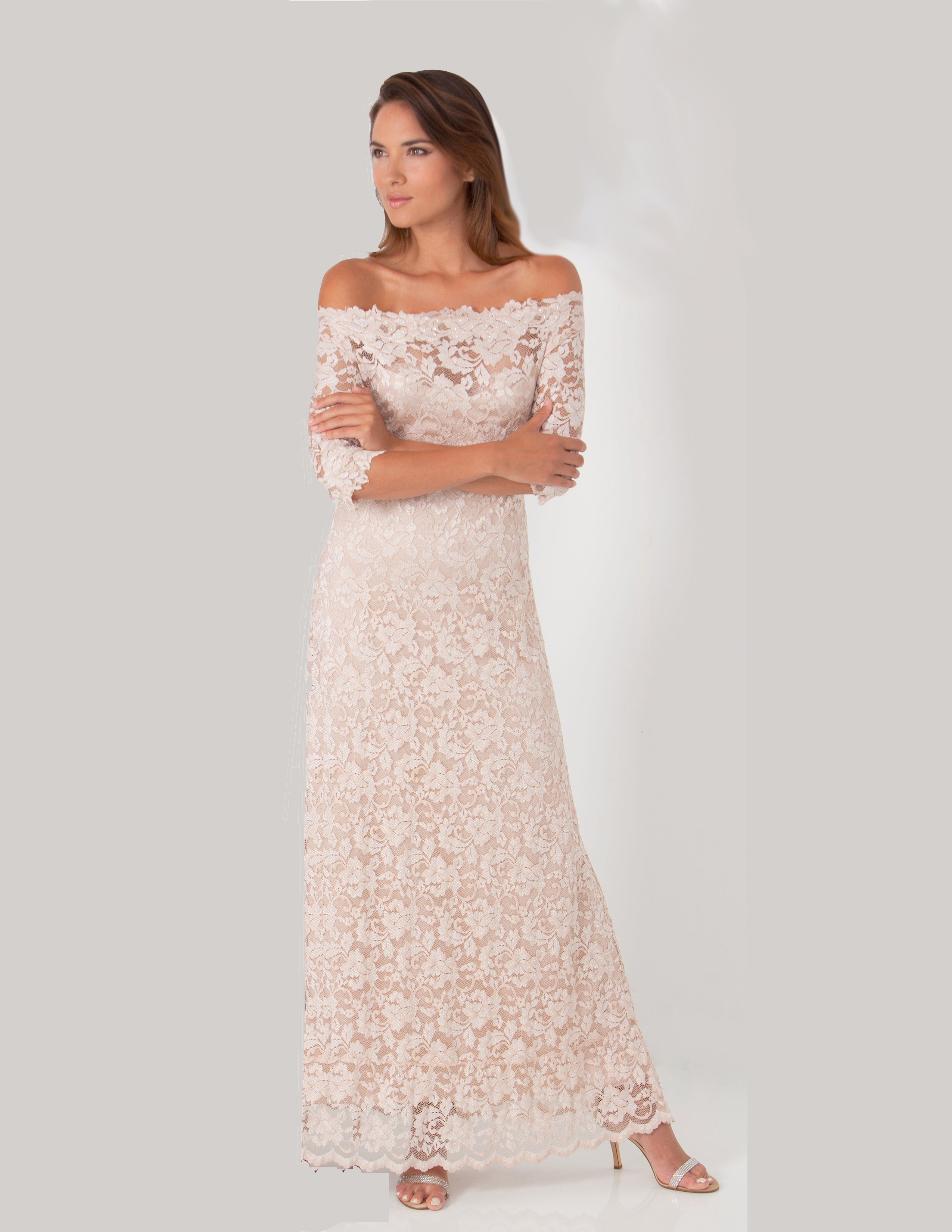 Woman wearing a white lace off-shoulder dress on a plain background