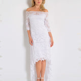 Woman wearing a white lace dress against a plain background