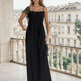 Woman in a black dress standing on a balcony with a cityscape background