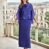 Woman in a sapphire outfit standing on a balcony with a cityscape in the background