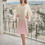 Woman in a light-colored dress standing on a balcony with a cityscape in the background