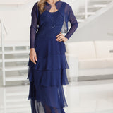 Woman wearing a blue dress with a matching jacket in a white room.