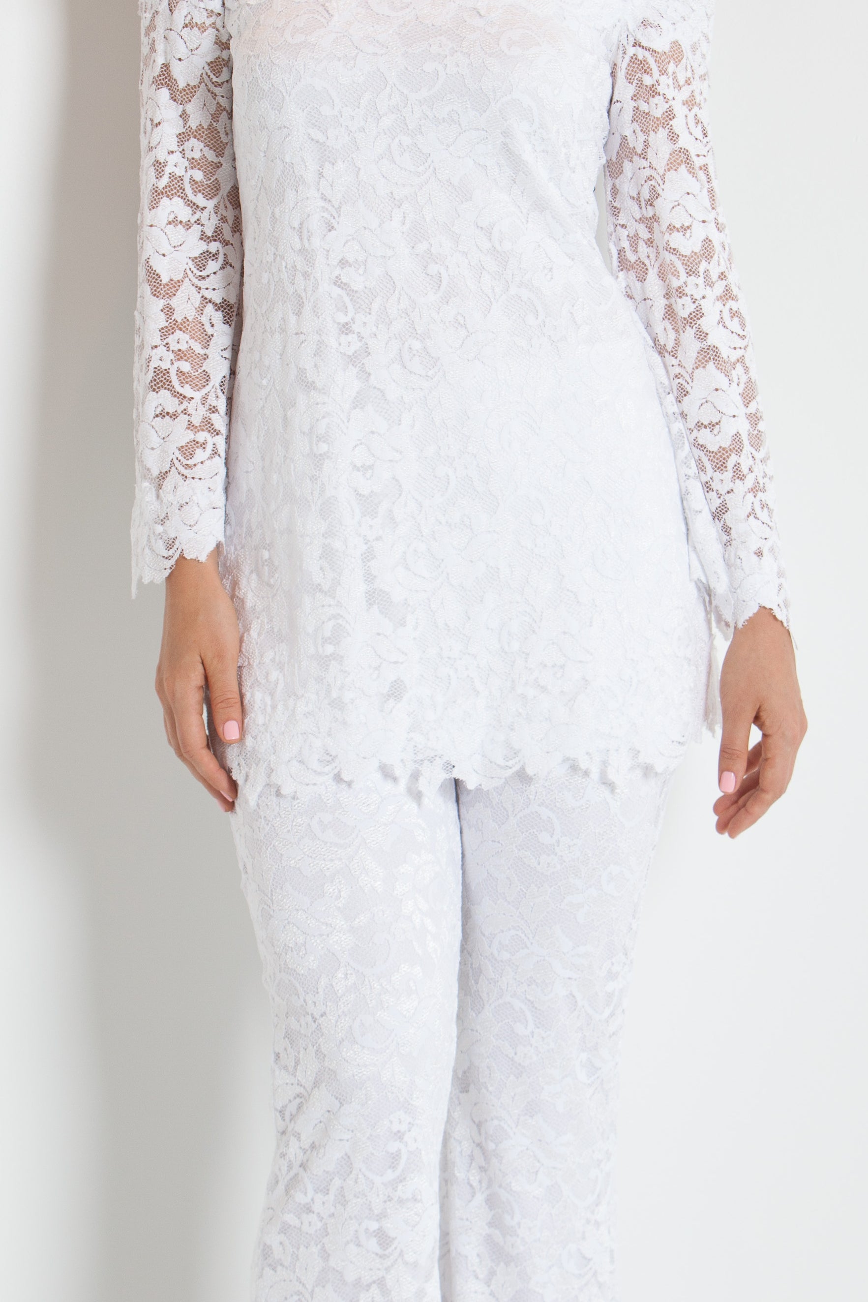 Woman wearing a white lace outfit against a white background