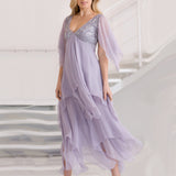 Woman wearing a lavender evening gown with a silver lace bodice on a white background