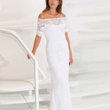 Woman standing in a white lace dress on a white staircase.