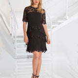 Woman wearing a black lace dress in a white interior setting