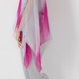 Woman wearing gray pants with a pink and gray poncho on a white background