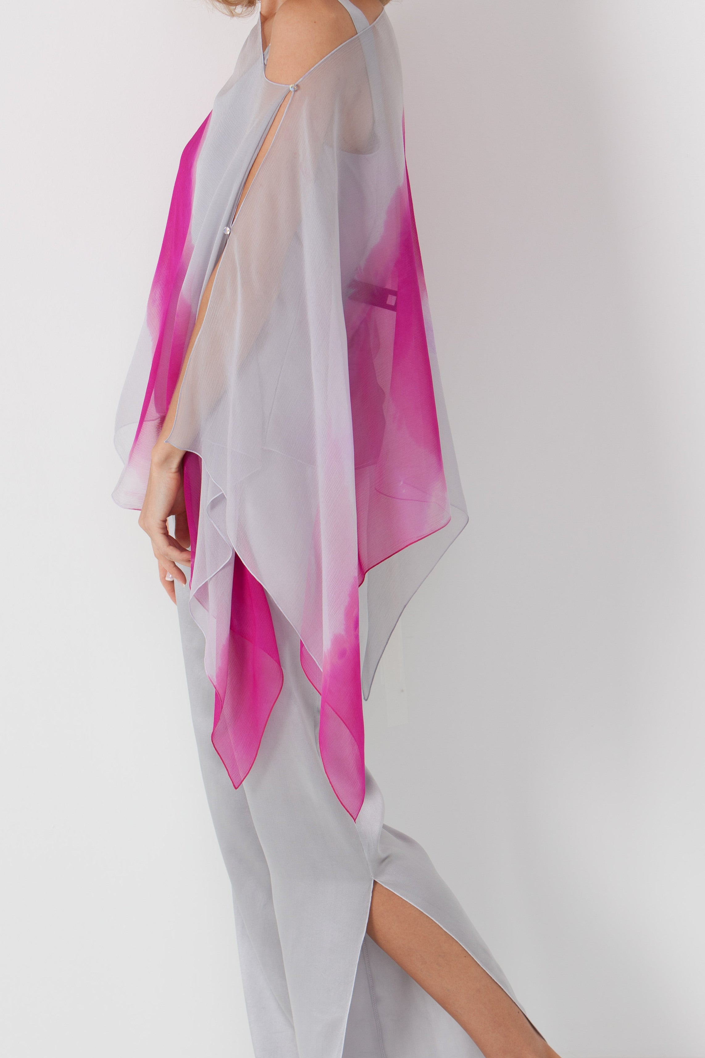 Woman wearing gray pants with a pink and gray poncho on a white background