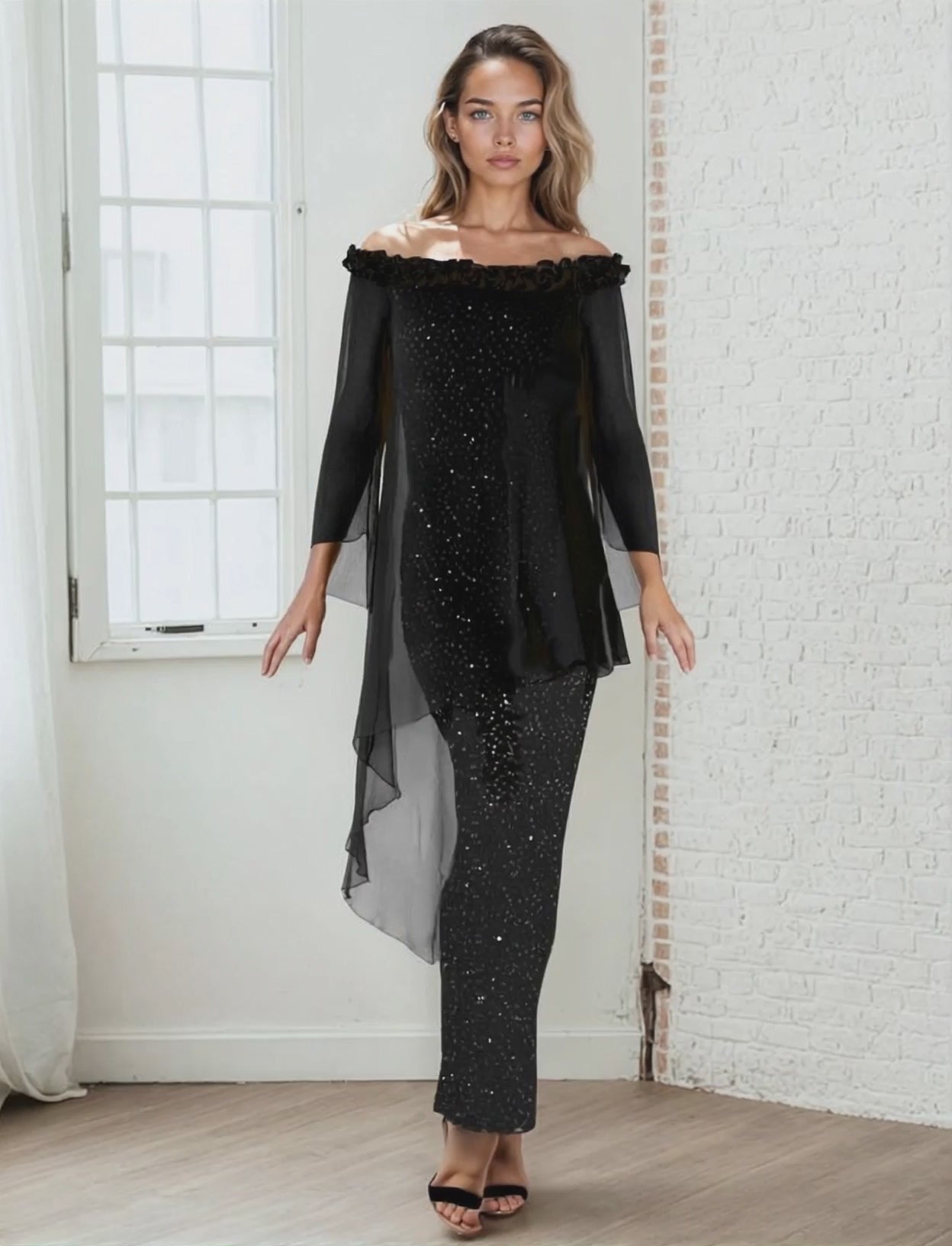 Woman wearing a black off-shoulder top and black sequin skirt in a room with white walls.
