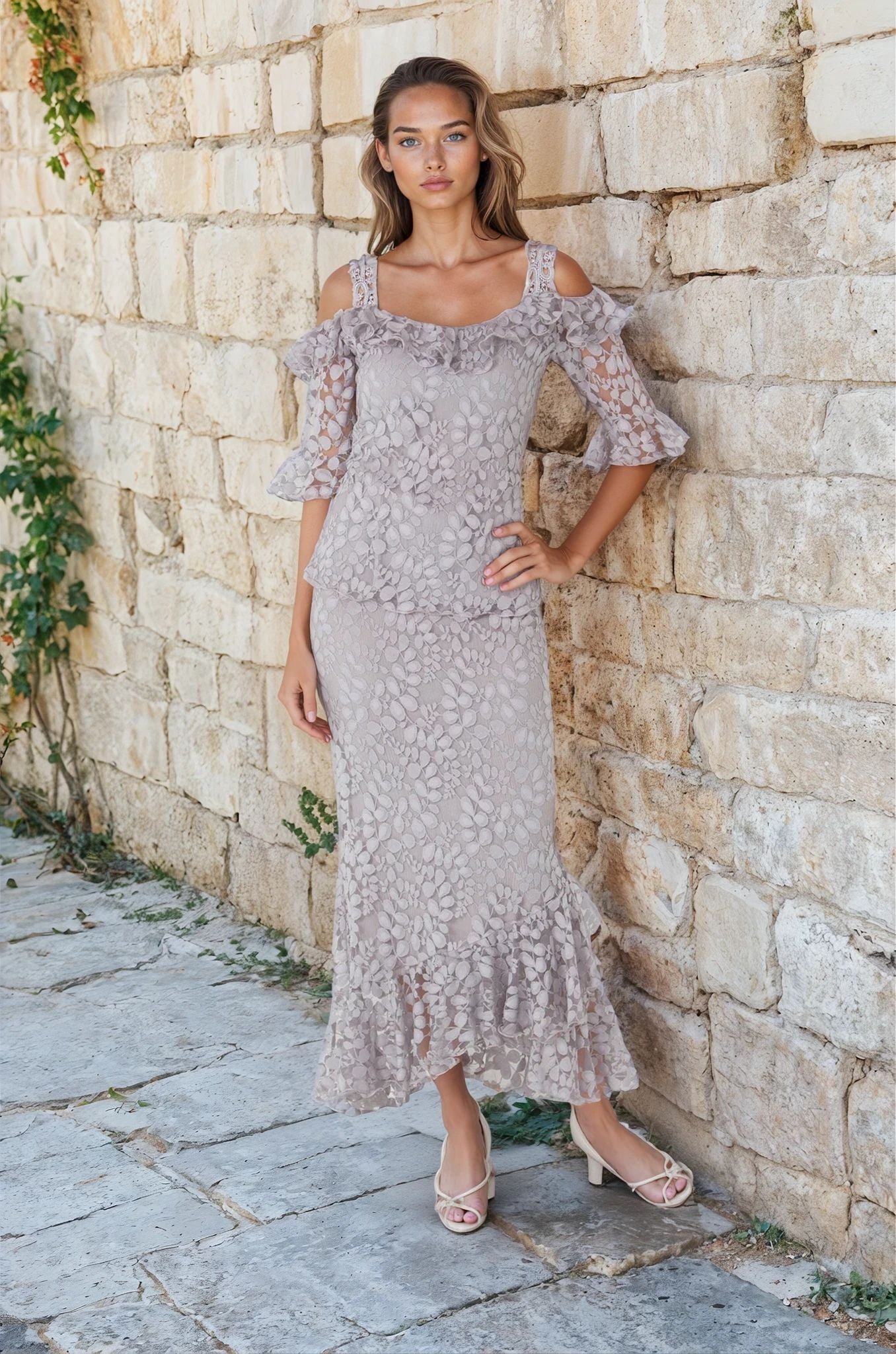Woman wearing gray lace two piece set against a garden wall