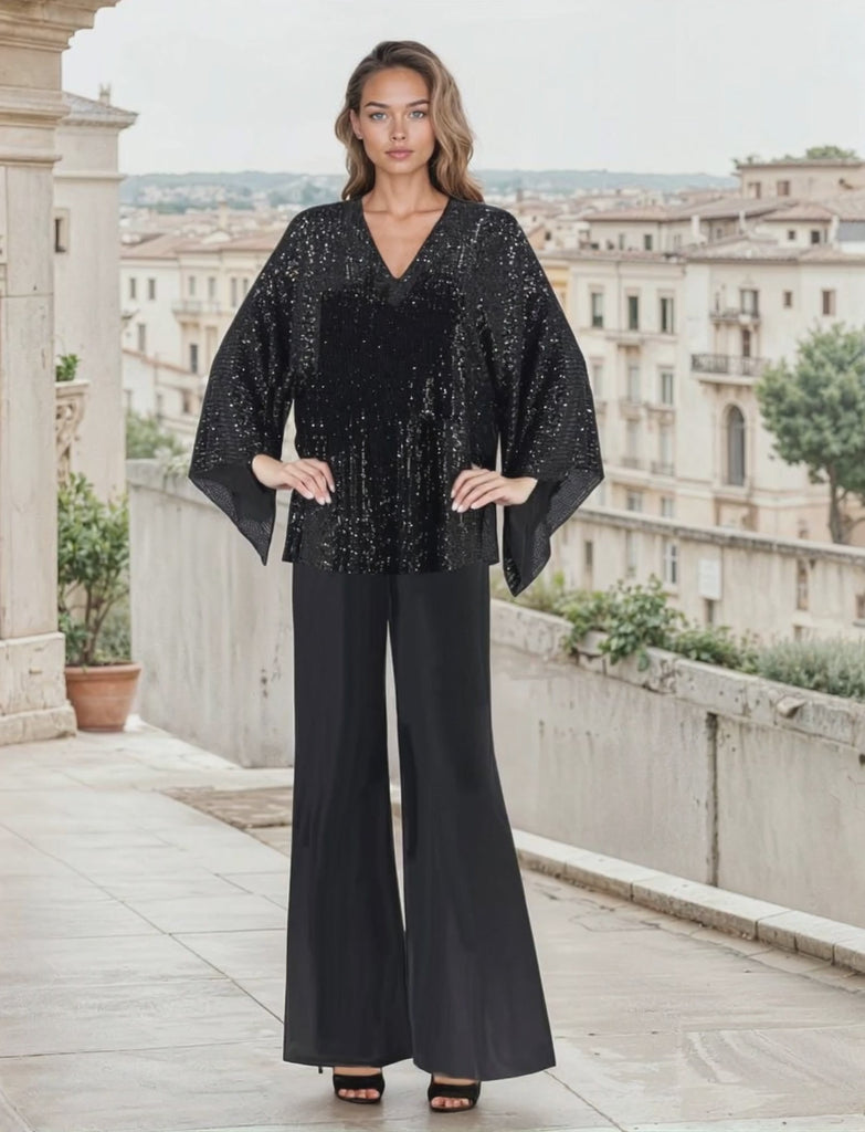 Woman in black seuin pant set standing on a city-scape balcony