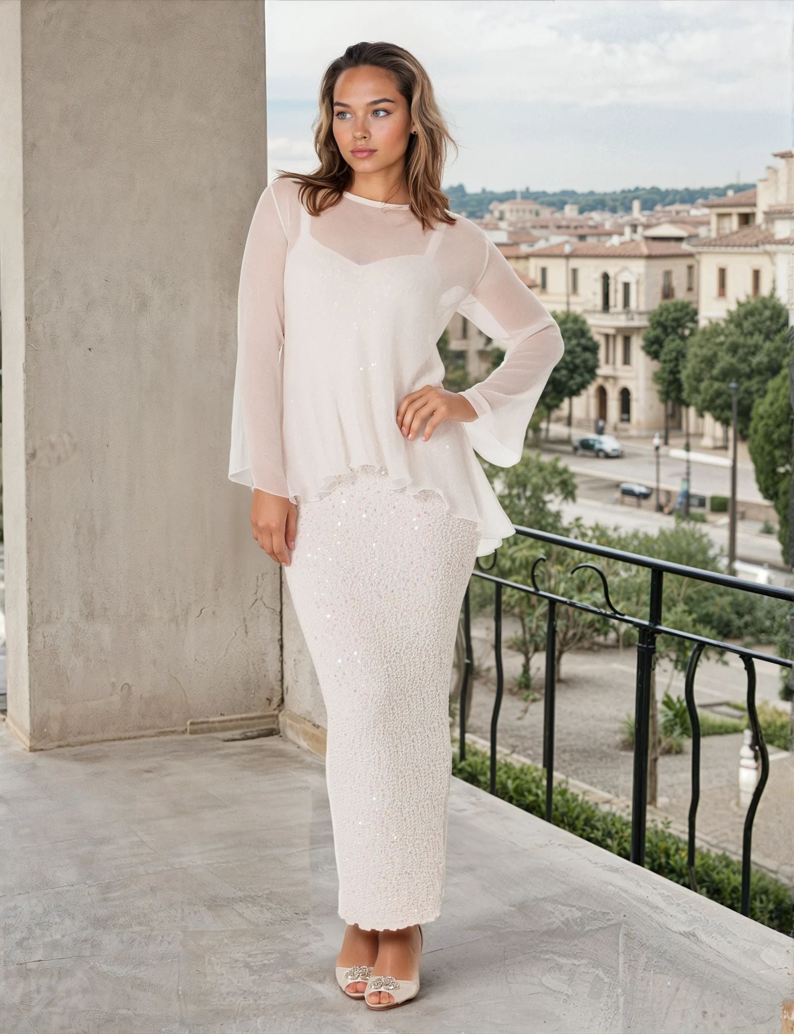 Woman in a white outfit standing on a balcony with a cityscape in the background