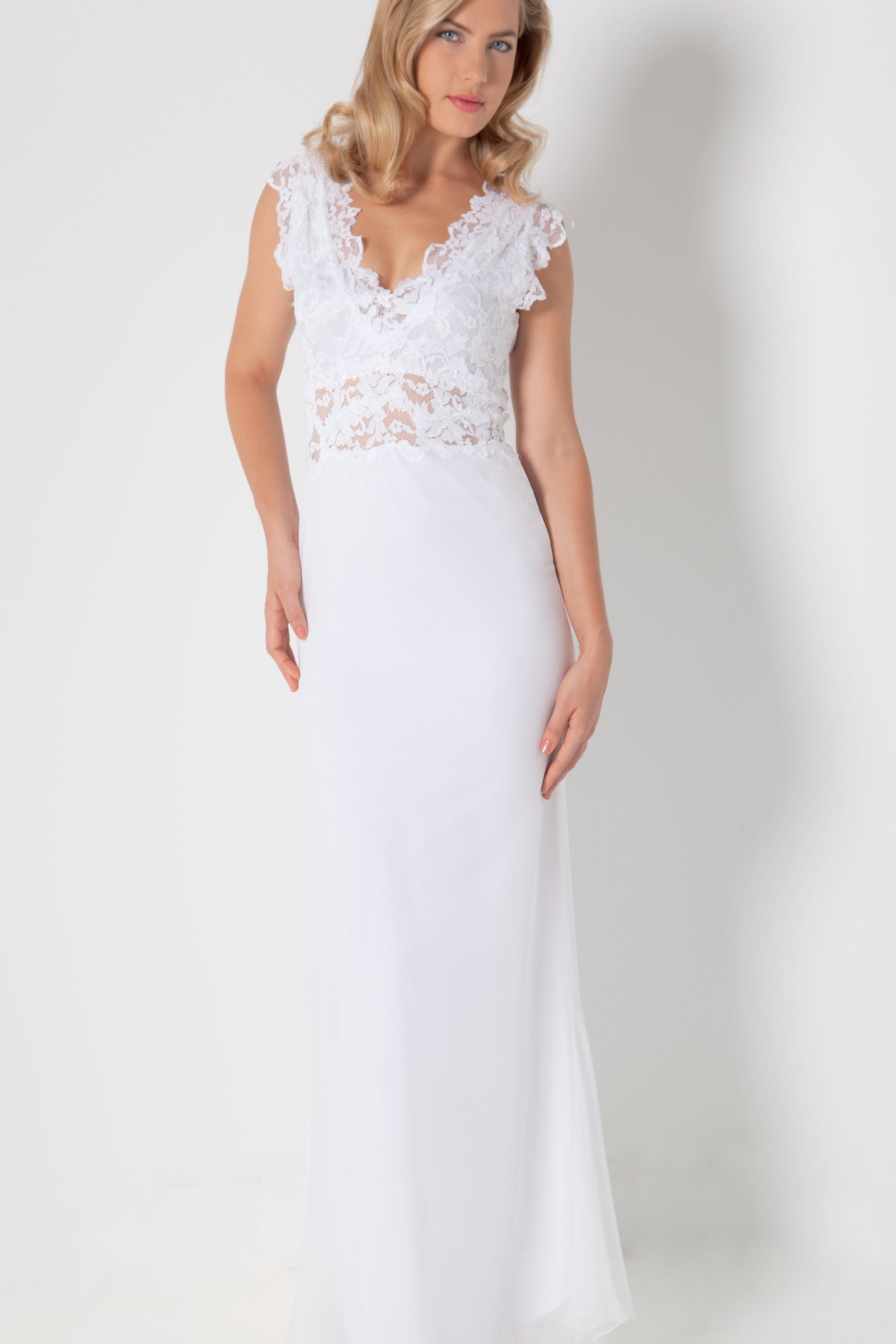 Woman in Full Length French Lace and Silk Plisse' white dress standing against a white wall